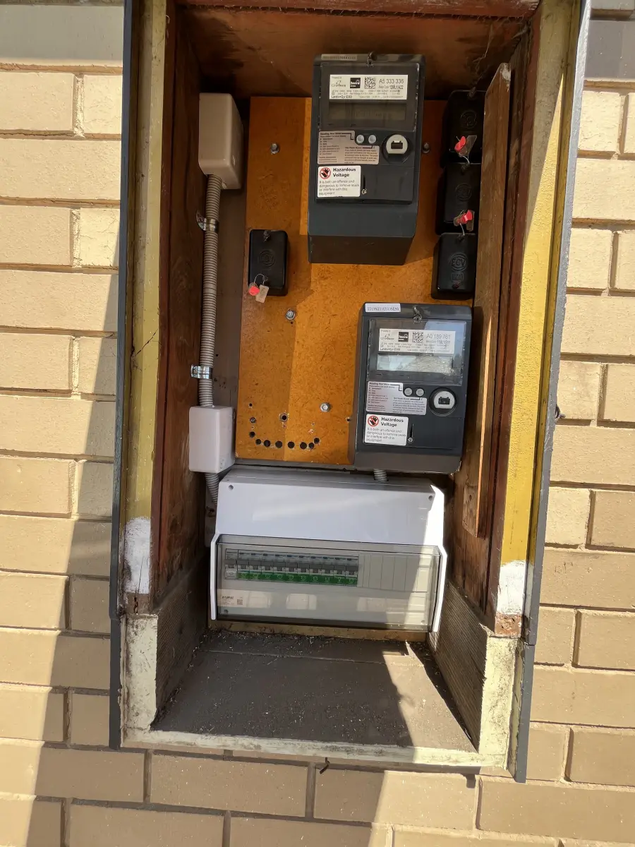 Older meter box with a new circuit breaker enclosure fitted alongside the existing meters
